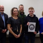 Kathy Plum/The Dominion Post Left to right are Preston Health Department Director V.J. Davis with Crystal and Patrick Pell, parents of Benjamin Pell (holding design), the Preston High student who designed the department's new logo. Far right is PHS teacher Janie Spahr, who teaches the digital imaging class in which Pell designed the logo.